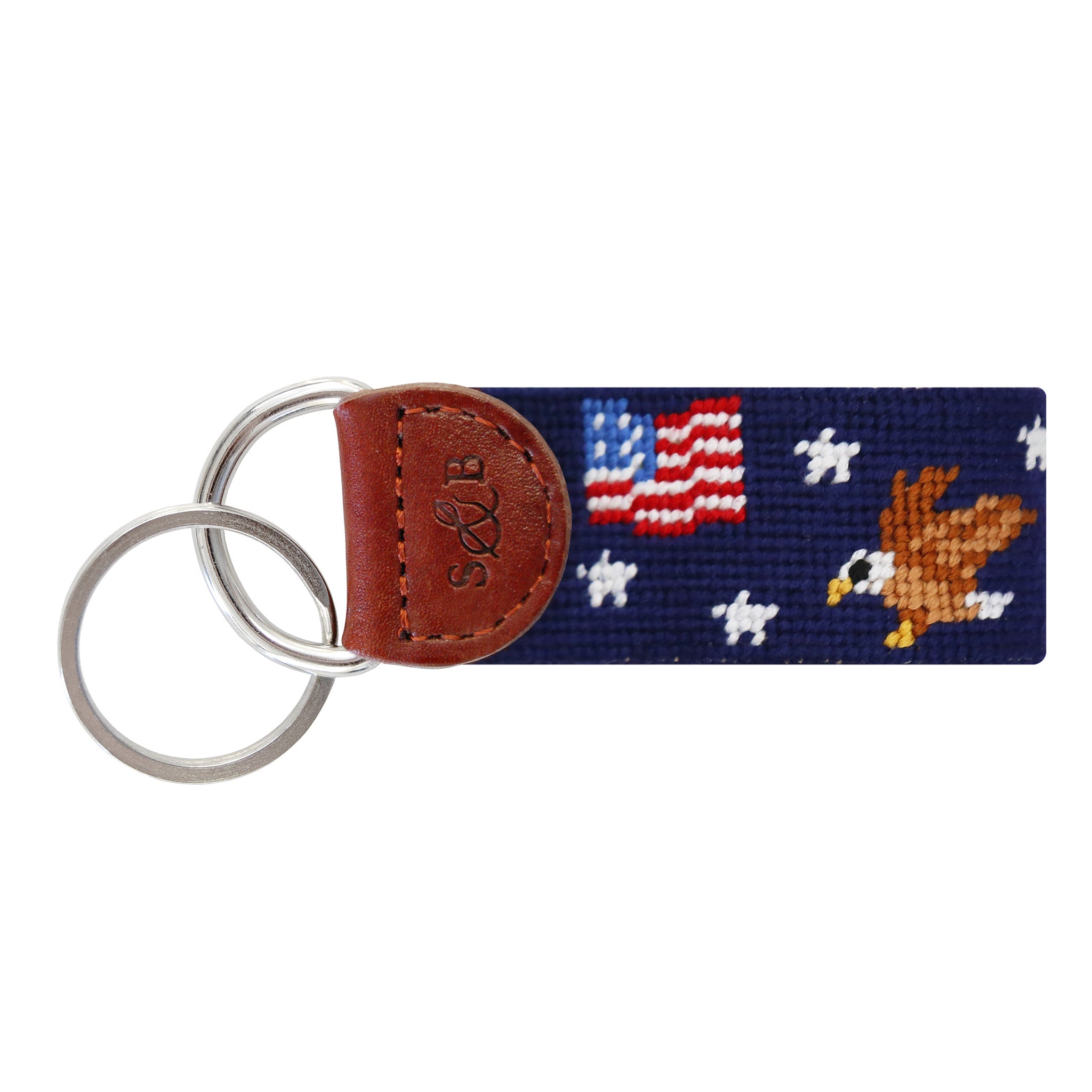 Dark navy needlepoint key fob with a red, white, and blue Americana star pattern, brown leather trim, and a metal key ring.