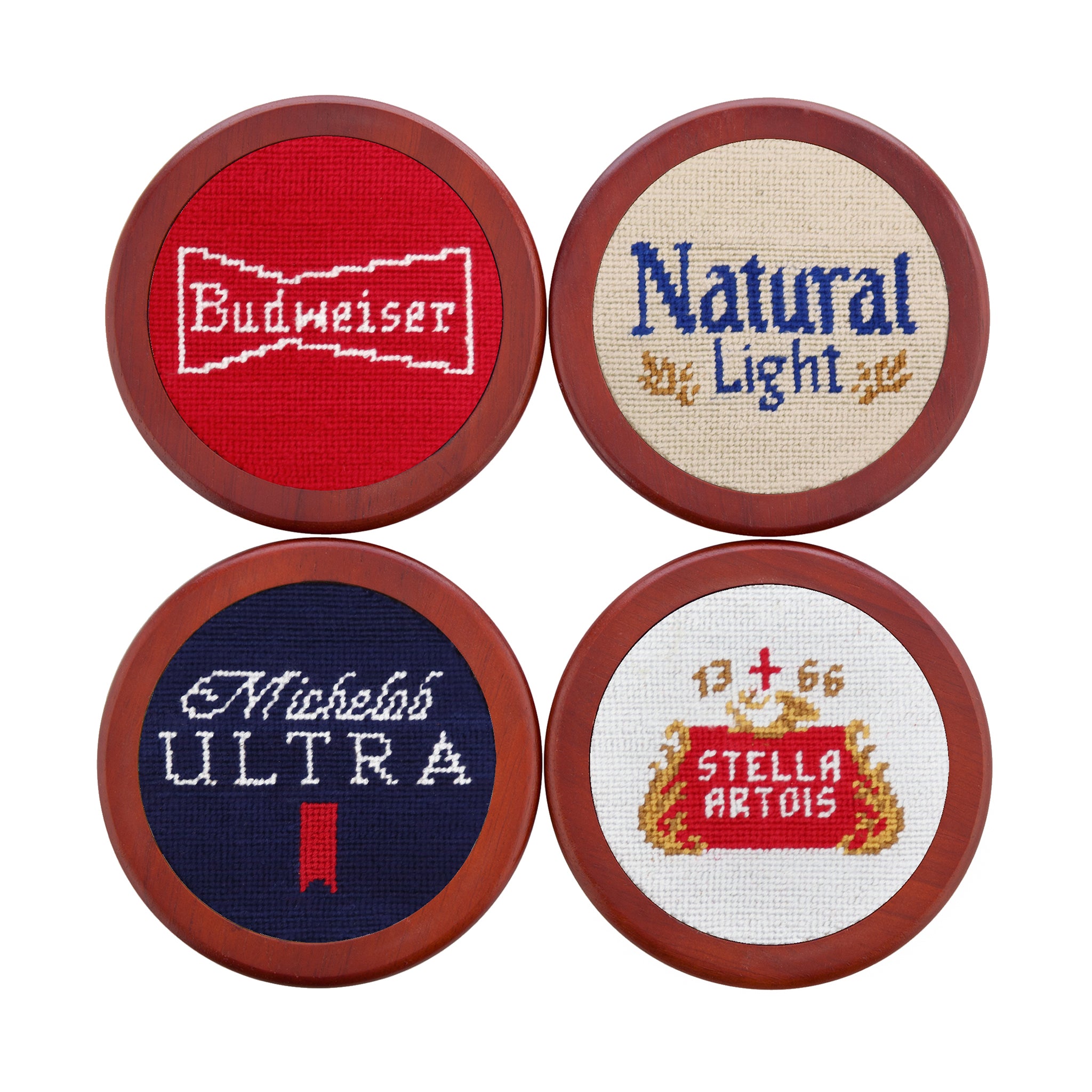 Coasters featuring vintage Anheuser-Busch beer label designs in needlepoint, shown laid flat.