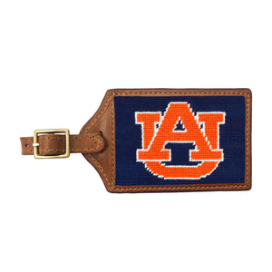 Navy needlepoint luggage tag featuring the orange and white Auburn “AU” logo, brown leather trim, and an ID window on the back.