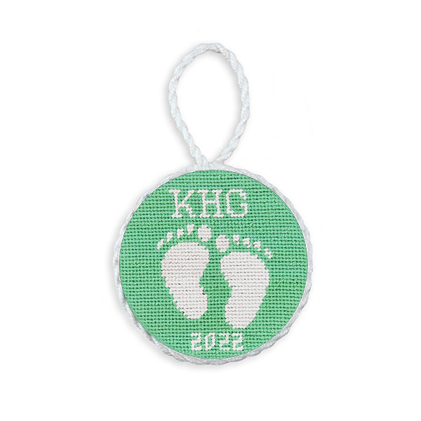 Mint green needlepoint ornament featuring baby feet, white hanging cord, 2022 edition.