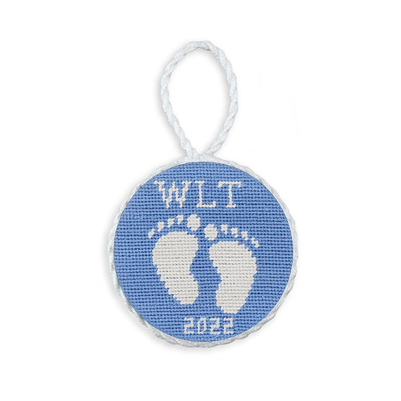 Light blue needlepoint ornament featuring baby feet, white hanging cord, 2022 edition.