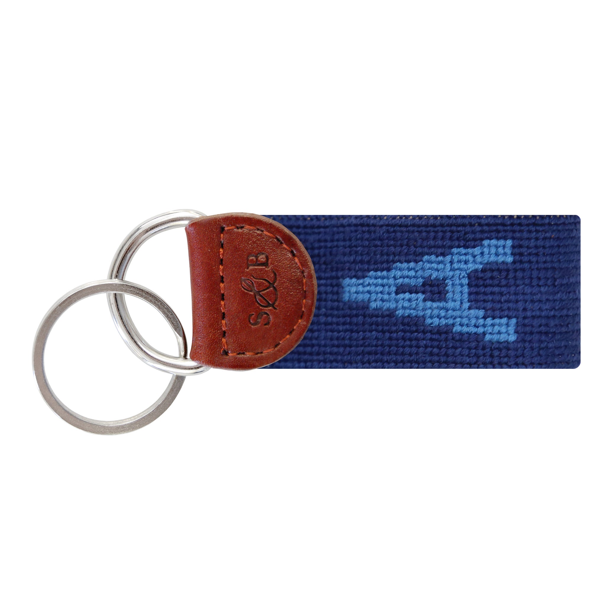Navy needlepoint key fob with a white block letter “A,” brown leather trim, and a metal key ring.