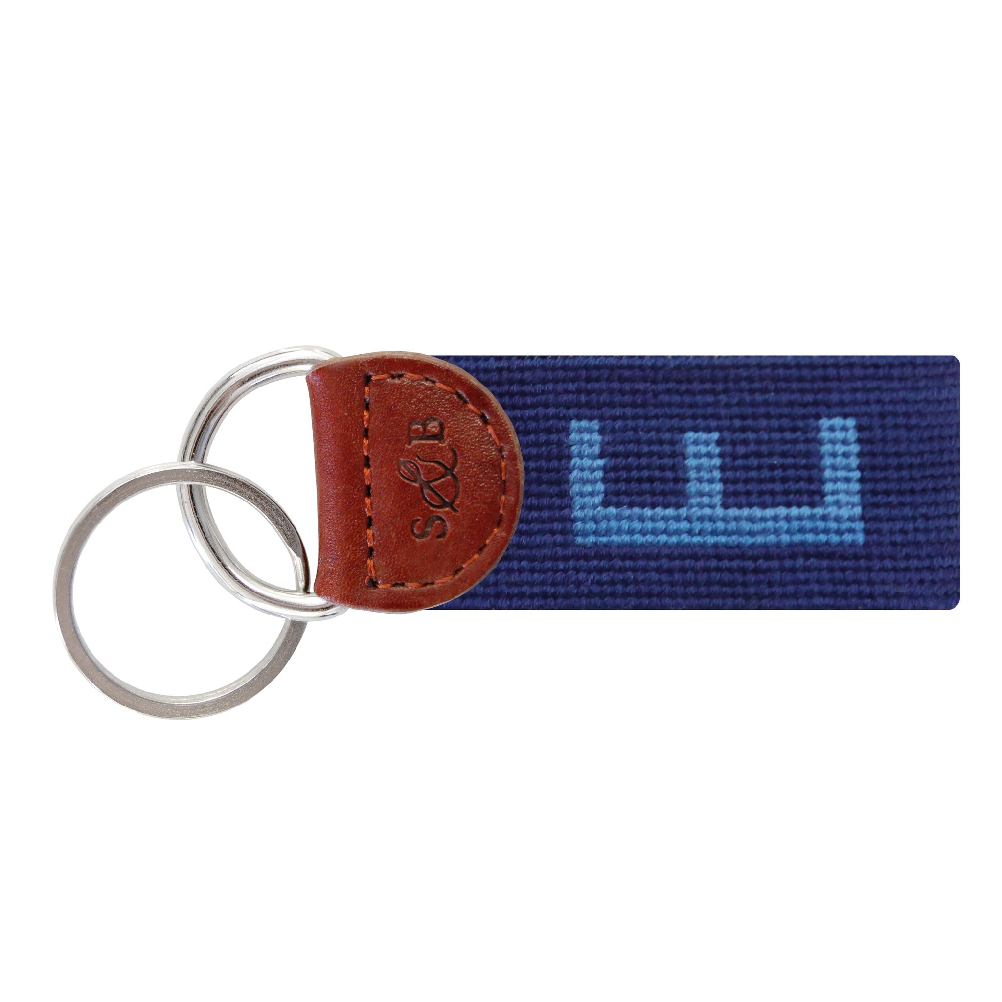 Navy needlepoint key fob featuring a white block letter “E,” brown leather trim, and a metal key ring.