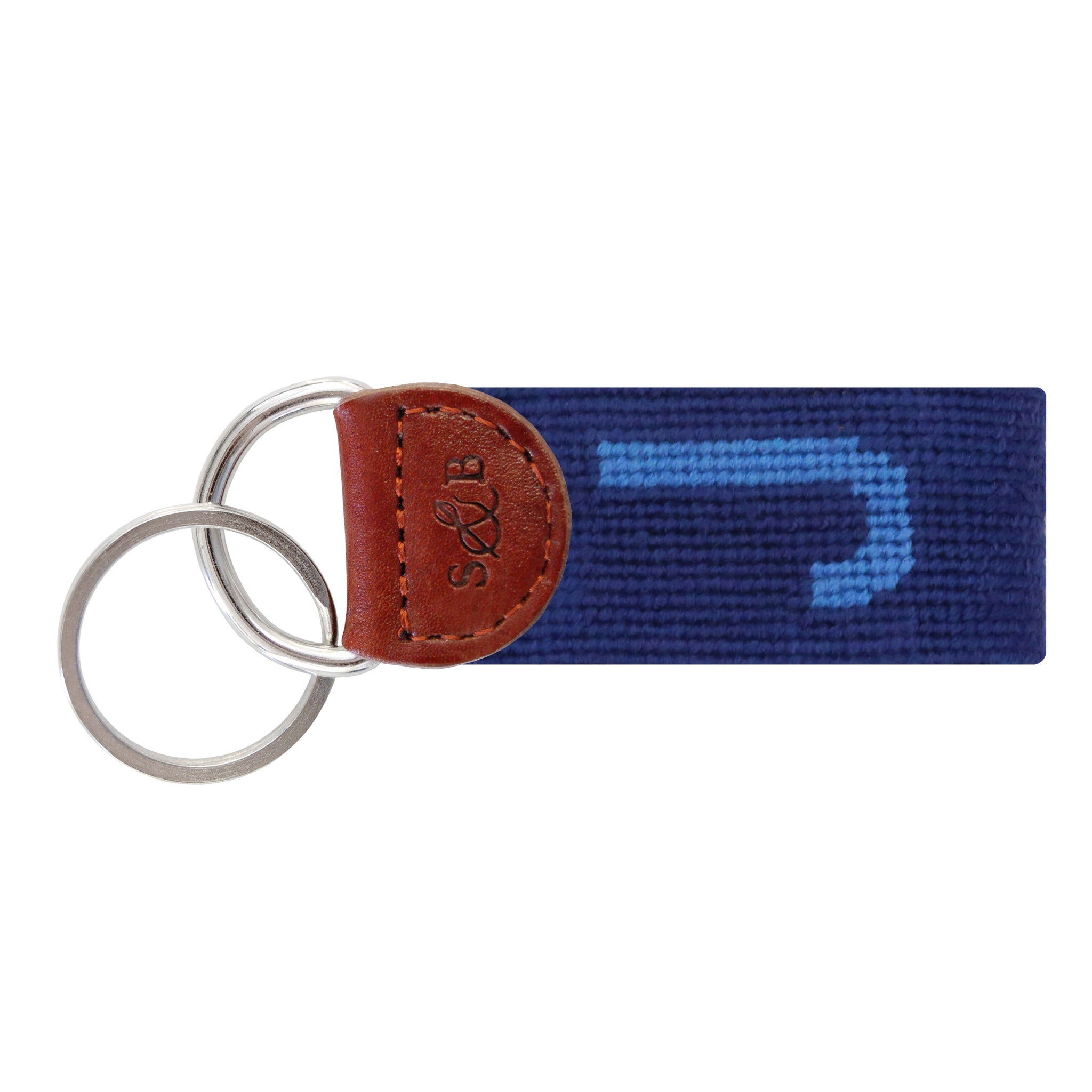 Navy needlepoint key fob with a white block letter “J,” brown leather trim, and a metal key ring.