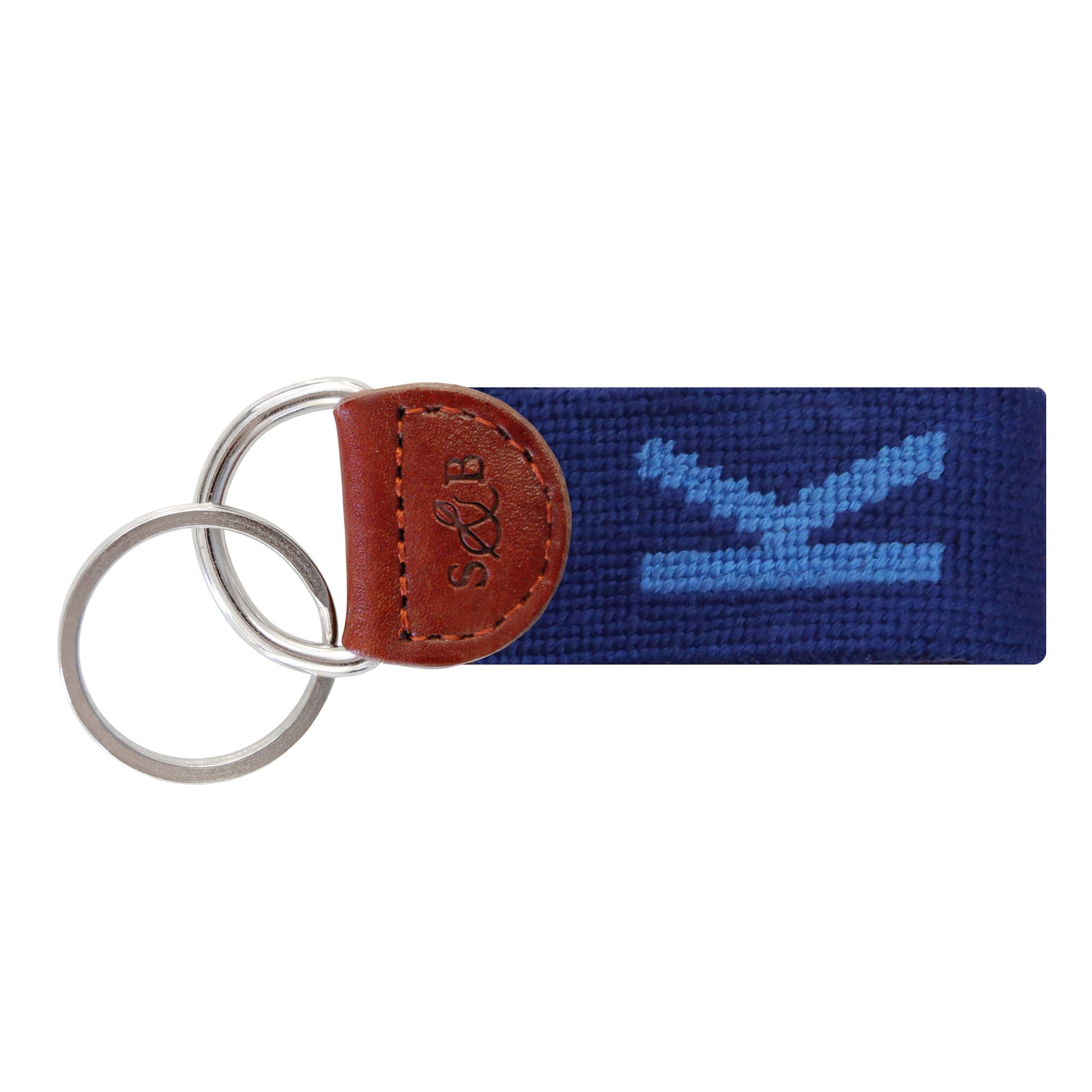 Navy needlepoint key fob featuring a white block letter “K,” brown leather trim, and a metal key ring.
