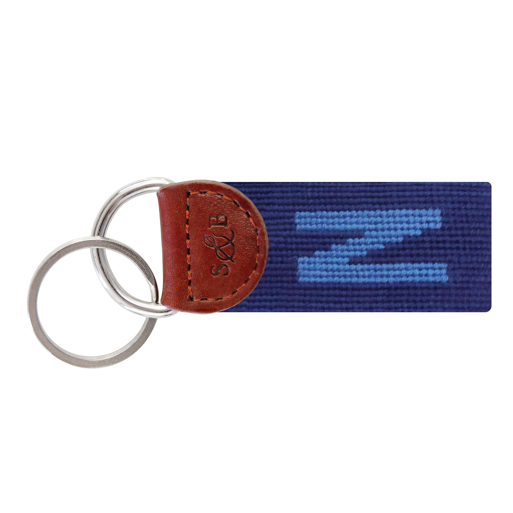 Navy needlepoint key fob featuring a white block letter “N,” brown leather trim, and a metal key ring.