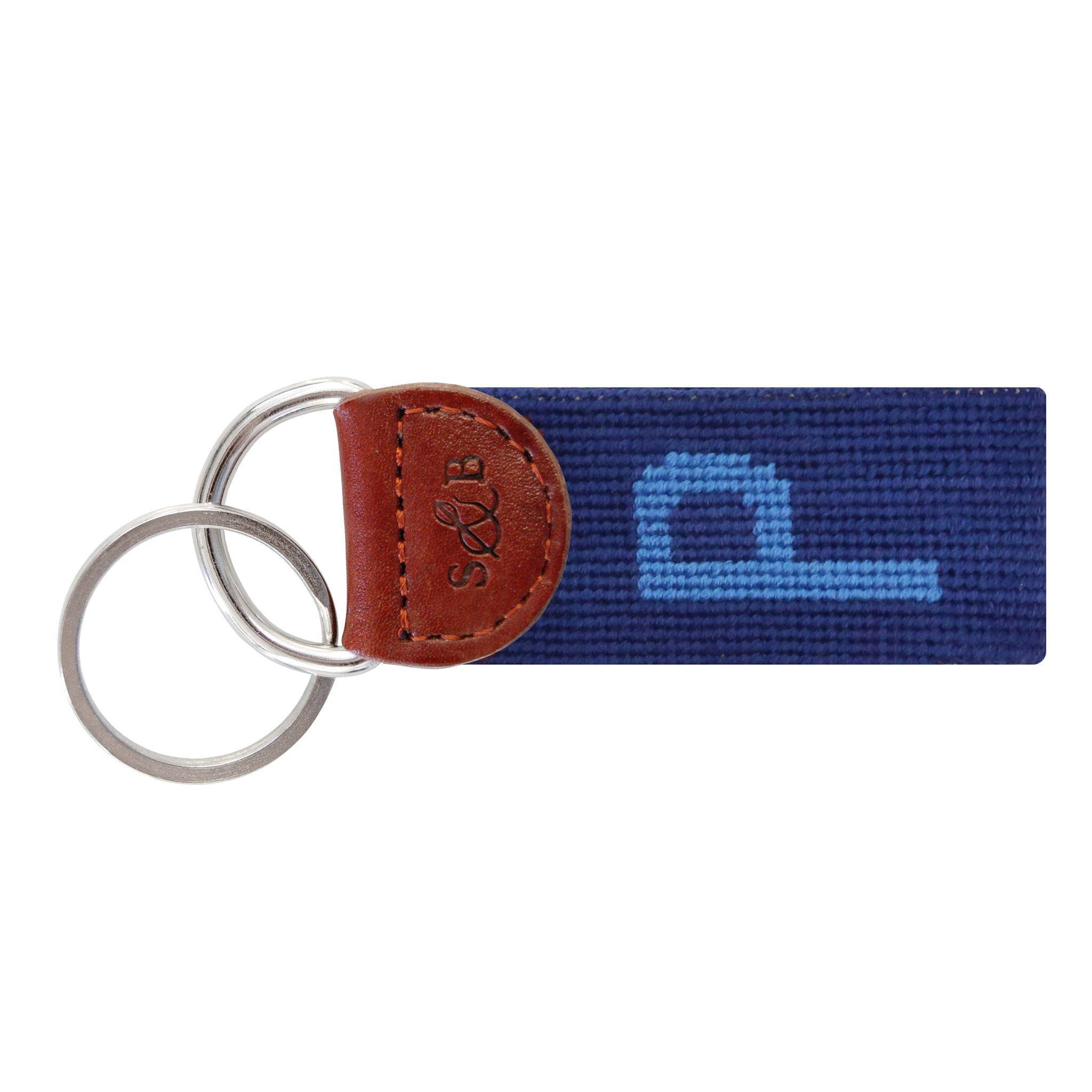 Navy needlepoint key fob with a white block letter “P,” brown leather trim, and a metal key ring.