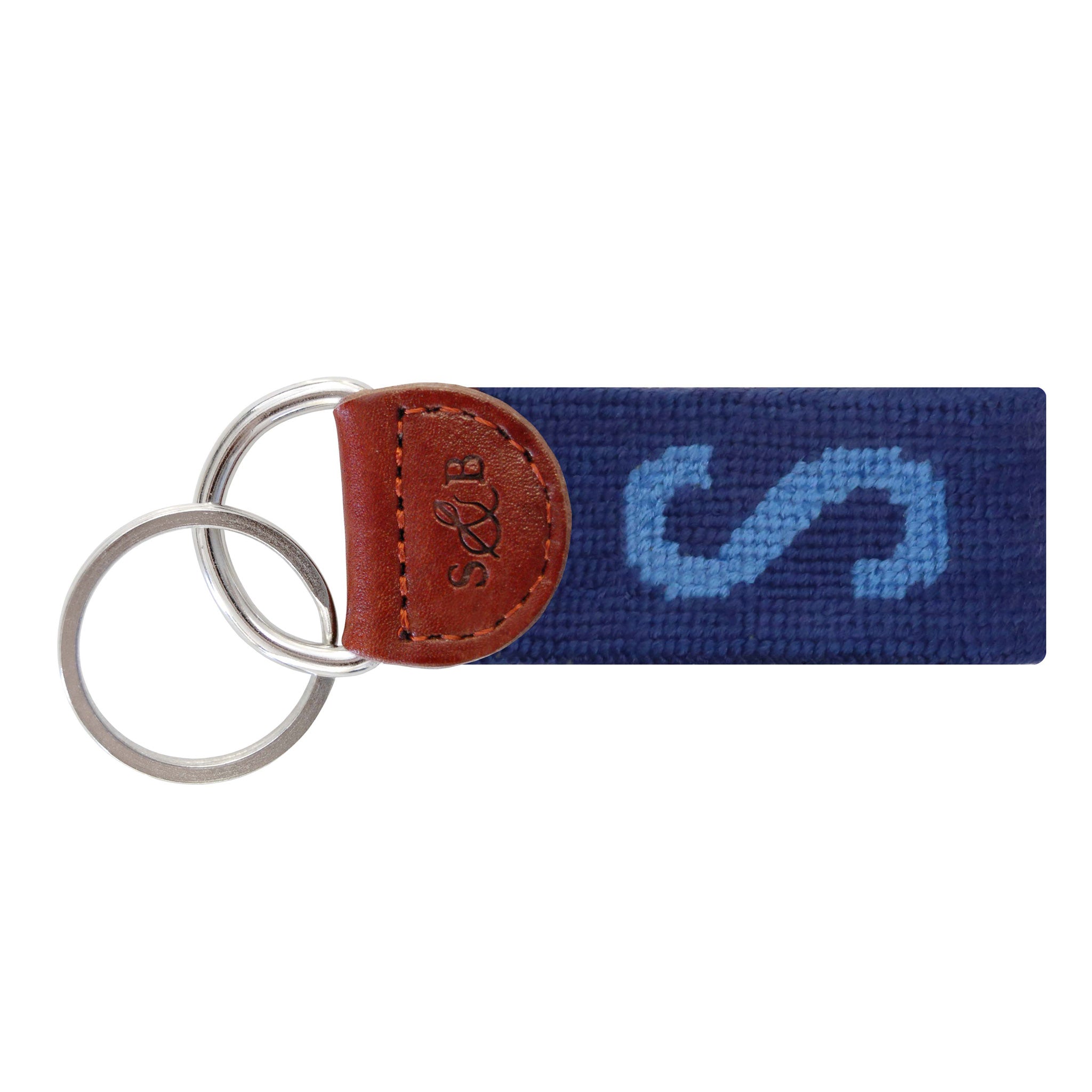 Navy needlepoint key fob with a white block letter “S,” brown leather trim, and a metal key ring.