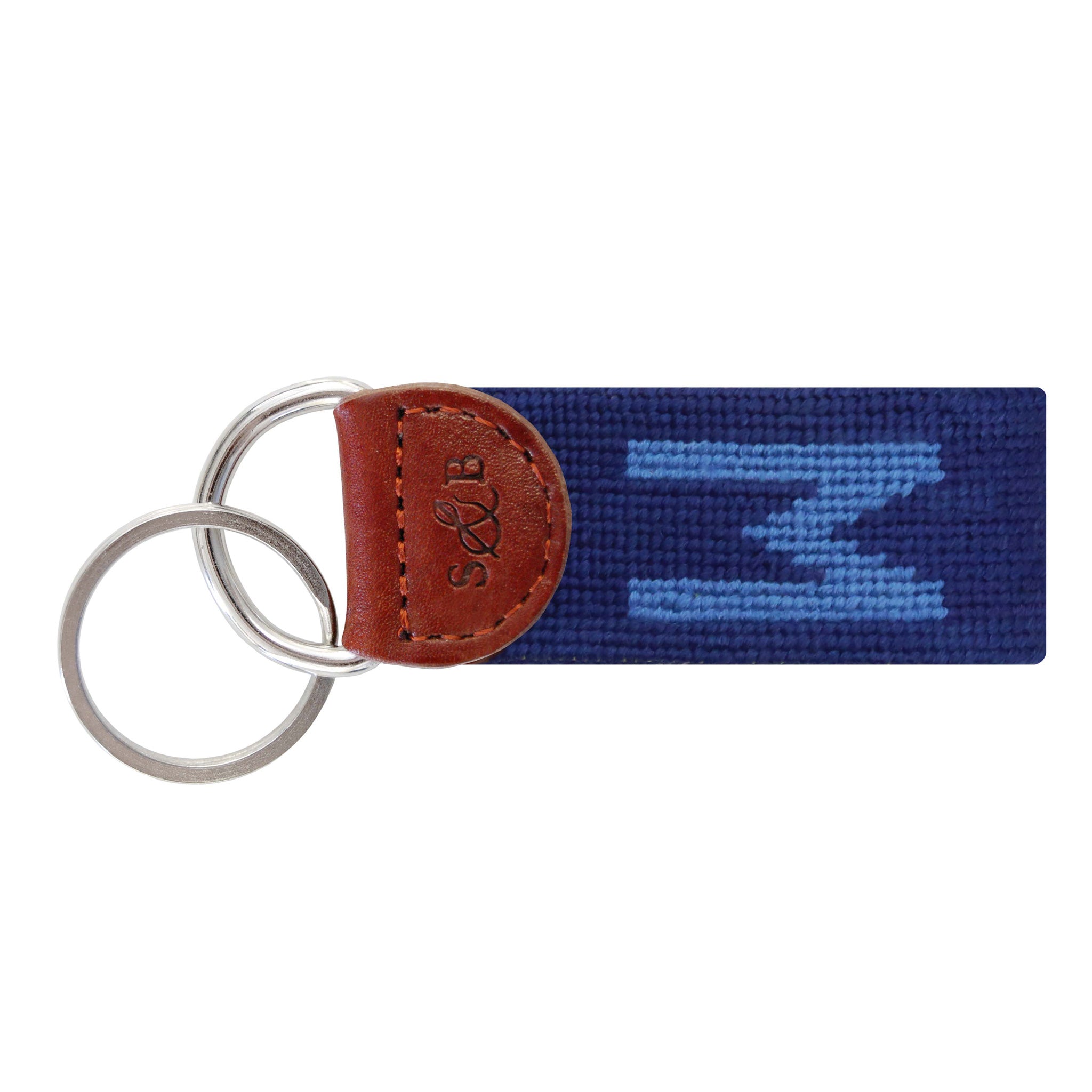 Navy needlepoint key fob featuring a white block letter “W,” brown leather trim, and a metal key ring.