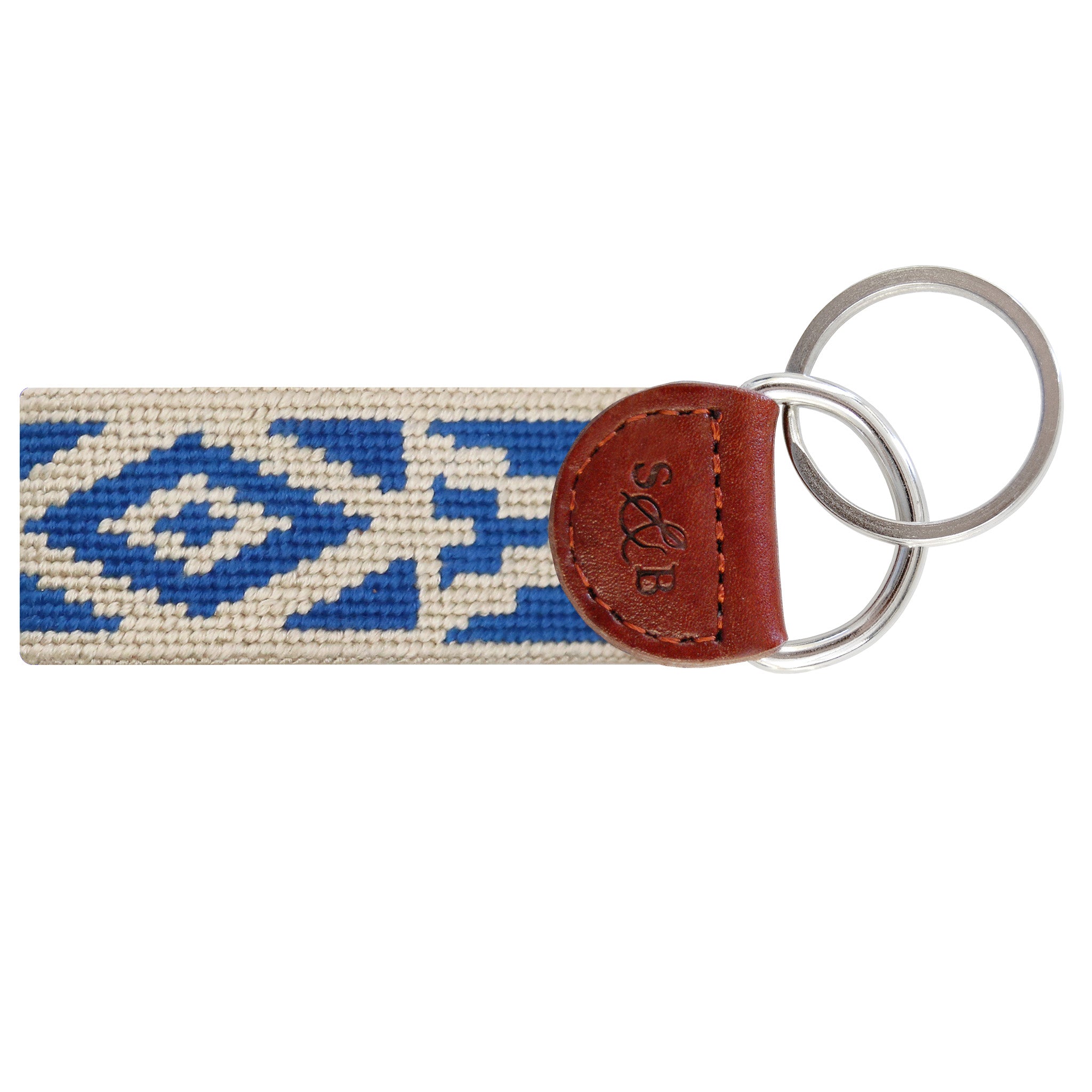 White needlepoint key fob featuring intricate geometric Cordoba tile details in red and blue, brown leather trim, and a metal key ring.