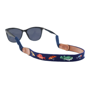 Dark navy needlepoint sunglass strap featuring Fish and Tackle pattern in lighter blue, with leather backing and cotton wrapped connectors for secure wear