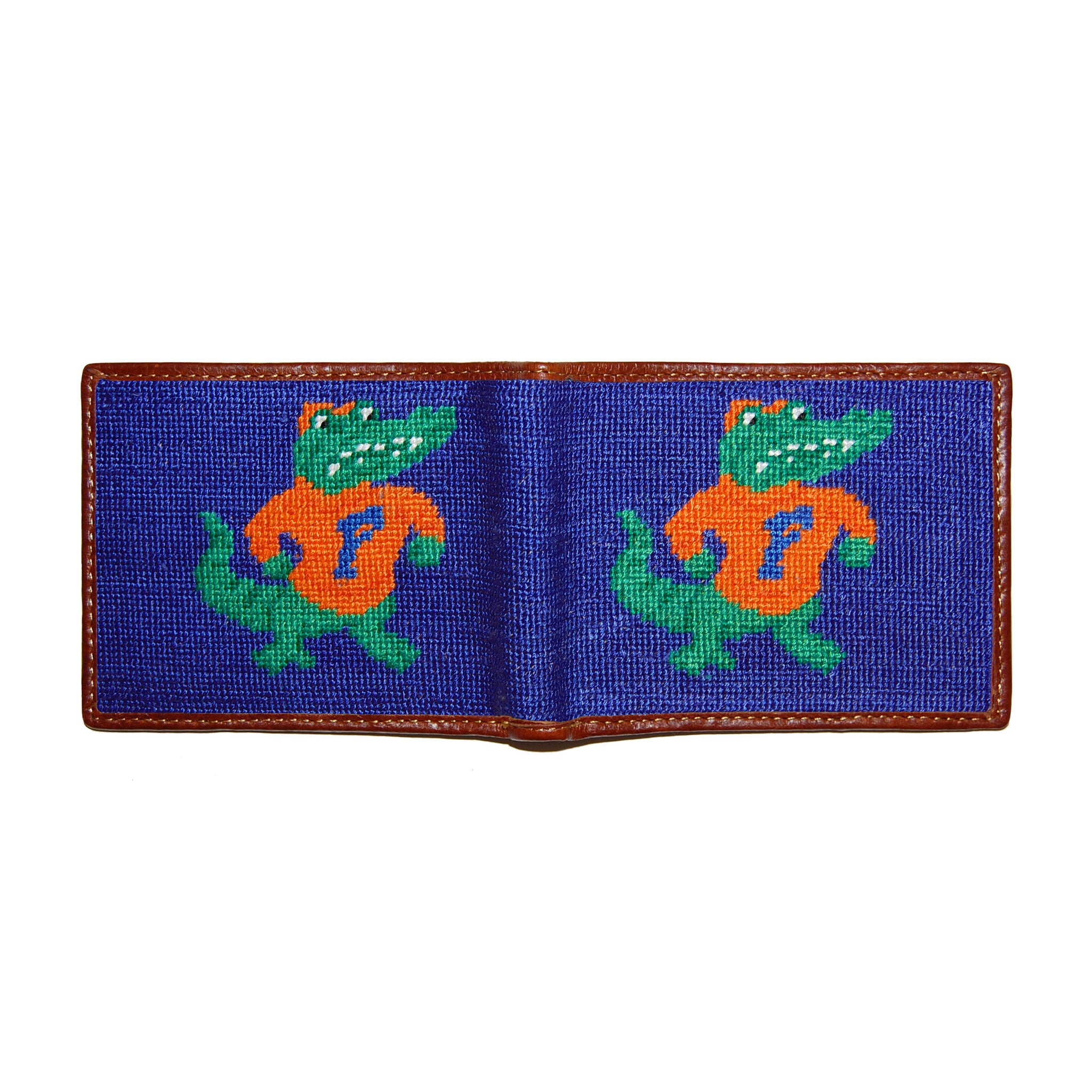 Florida orange and navy needlepoint bi-fold wallet open to show both sides of the white “Gators” script logo needlepoint design with brown leather trim.