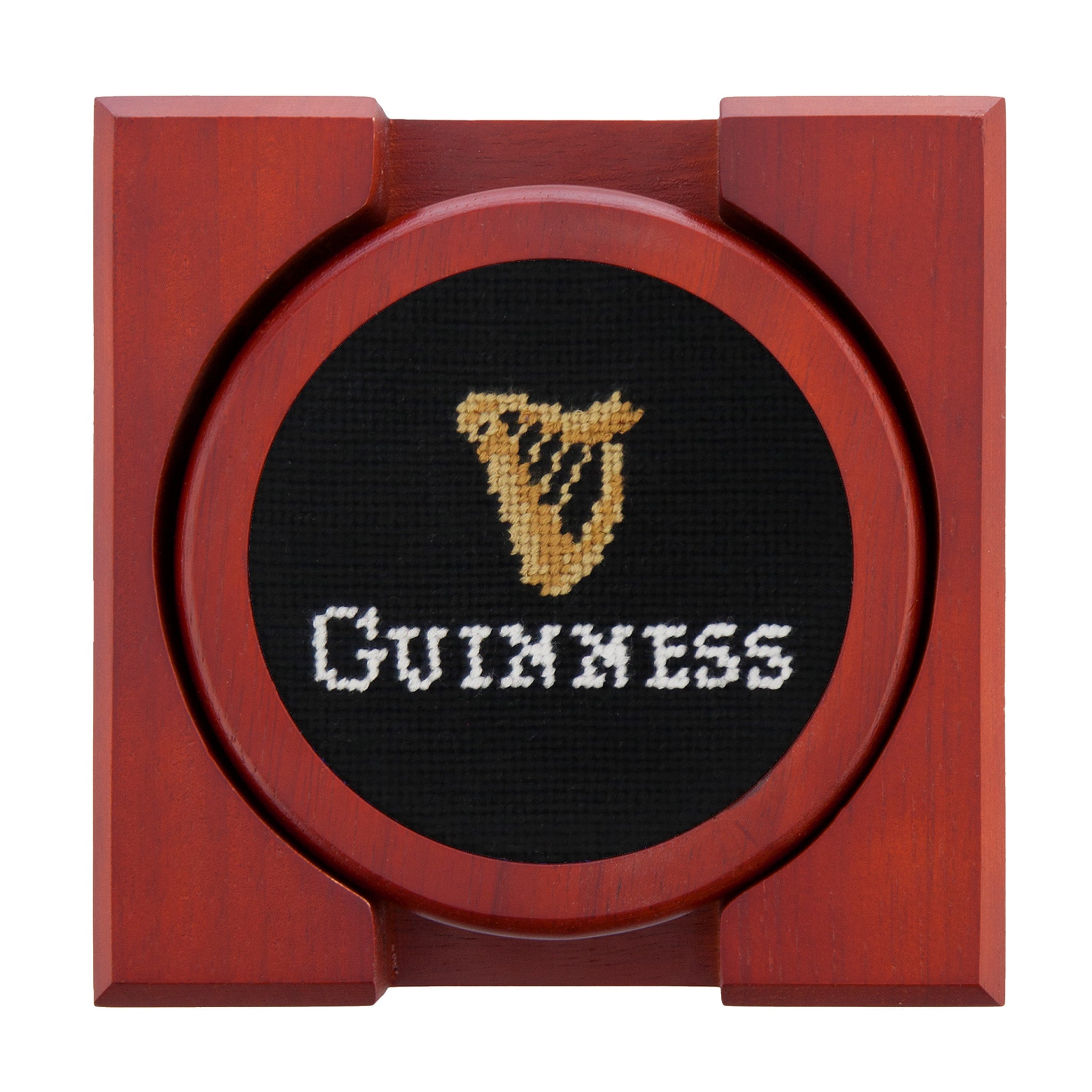 Set of four round wooden coasters with stitched needlepoint logos stacked neatly in a wooden holder.