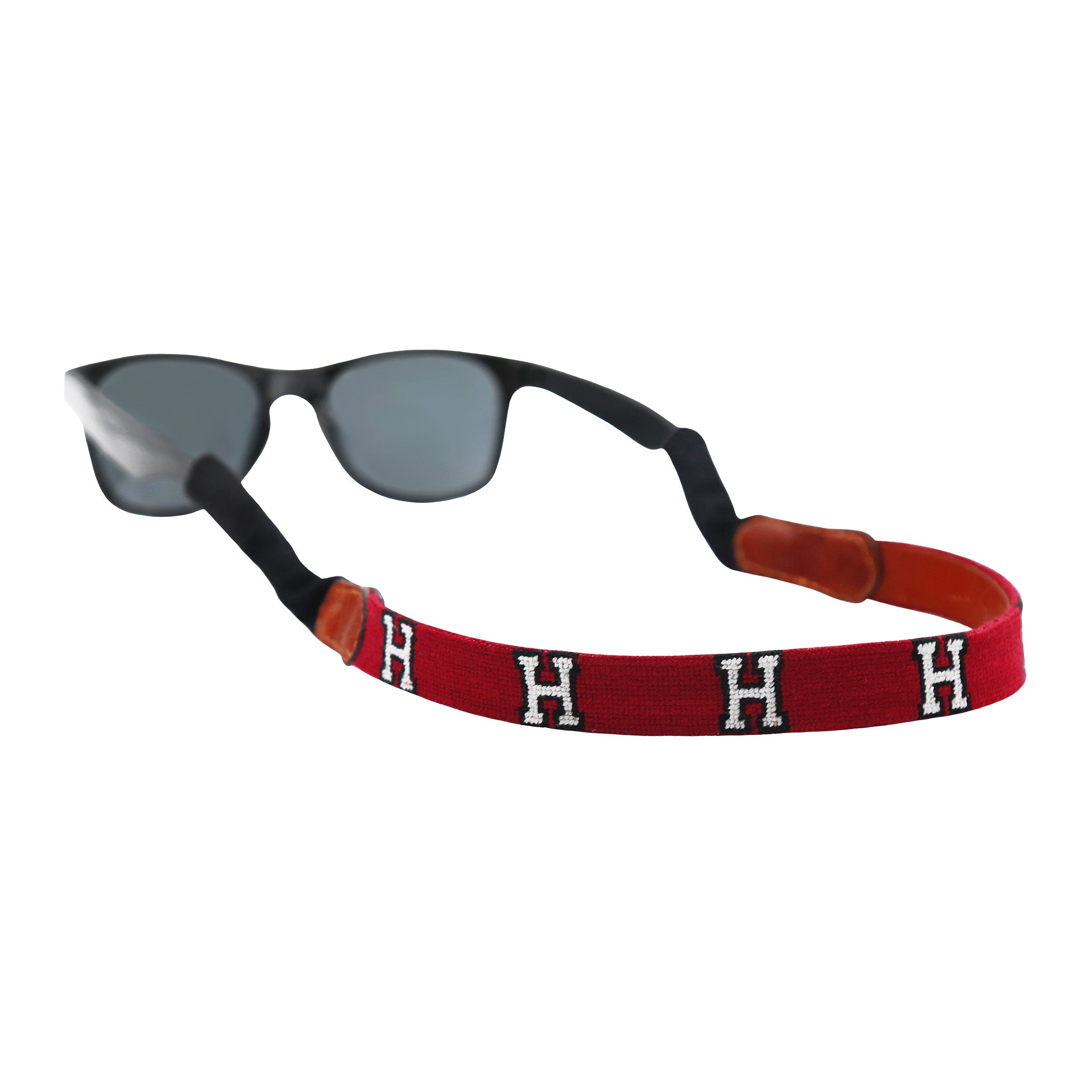 Garnet needlepoint sunglass strap featuring the Harvard logo stitched in white, with leather backing and cotton wrapped connectors for secure wear