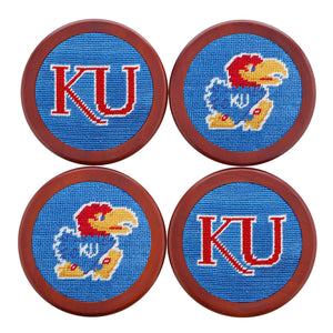 Blue needlepoint coaster set showcasing the Kansas Jayhawk logo in red and yellow, with chestnut wood backing.
