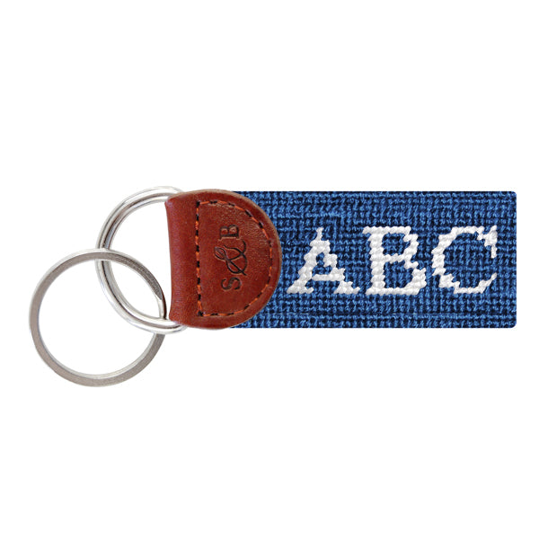 Blueberry needlepoint key fob with white monogram initials, brown leather trim, and a metal key ring.
