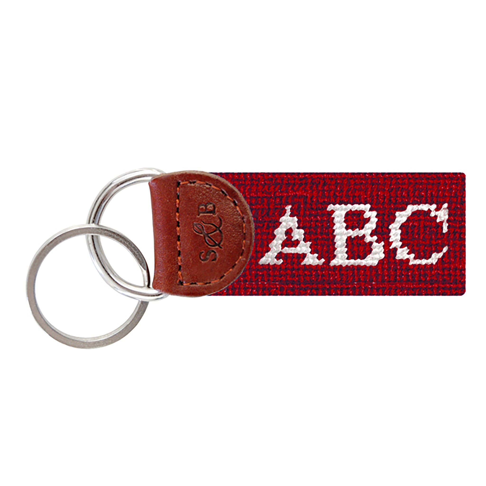 Garnet needlepoint key fob with white monogram initials, brown leather trim, and a metal key ring.