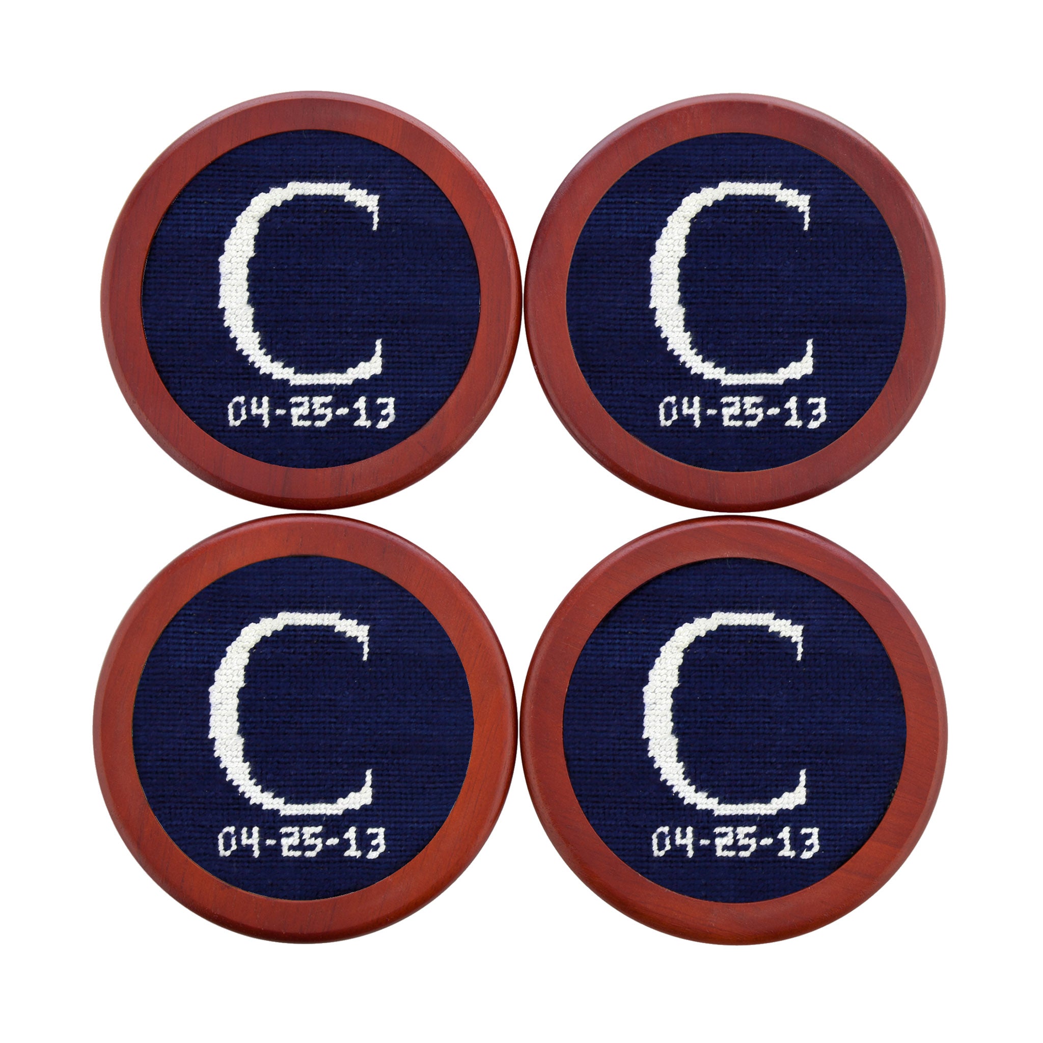 Coaster featuring a stitched design of a letter and date in black and red on a light background, shown laid flat.