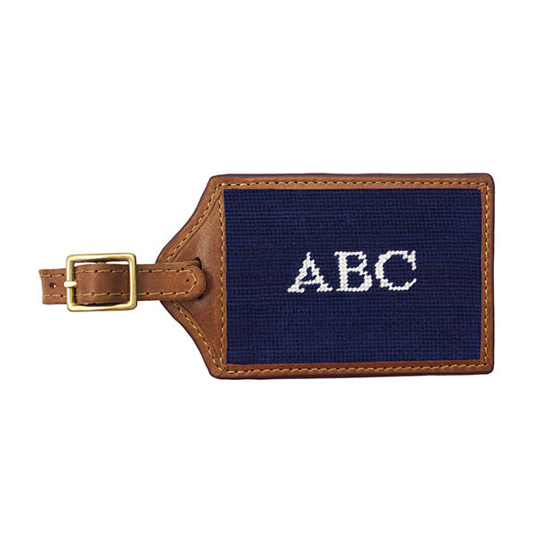 Blueberry needlepoint luggage tag with white Block 10 monogram initials, brown leather trim, and an ID window on the back.