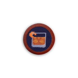 Dark navy golf ball marker with the phrase “Make an Old Fashioned” stitched in white needlepoint.