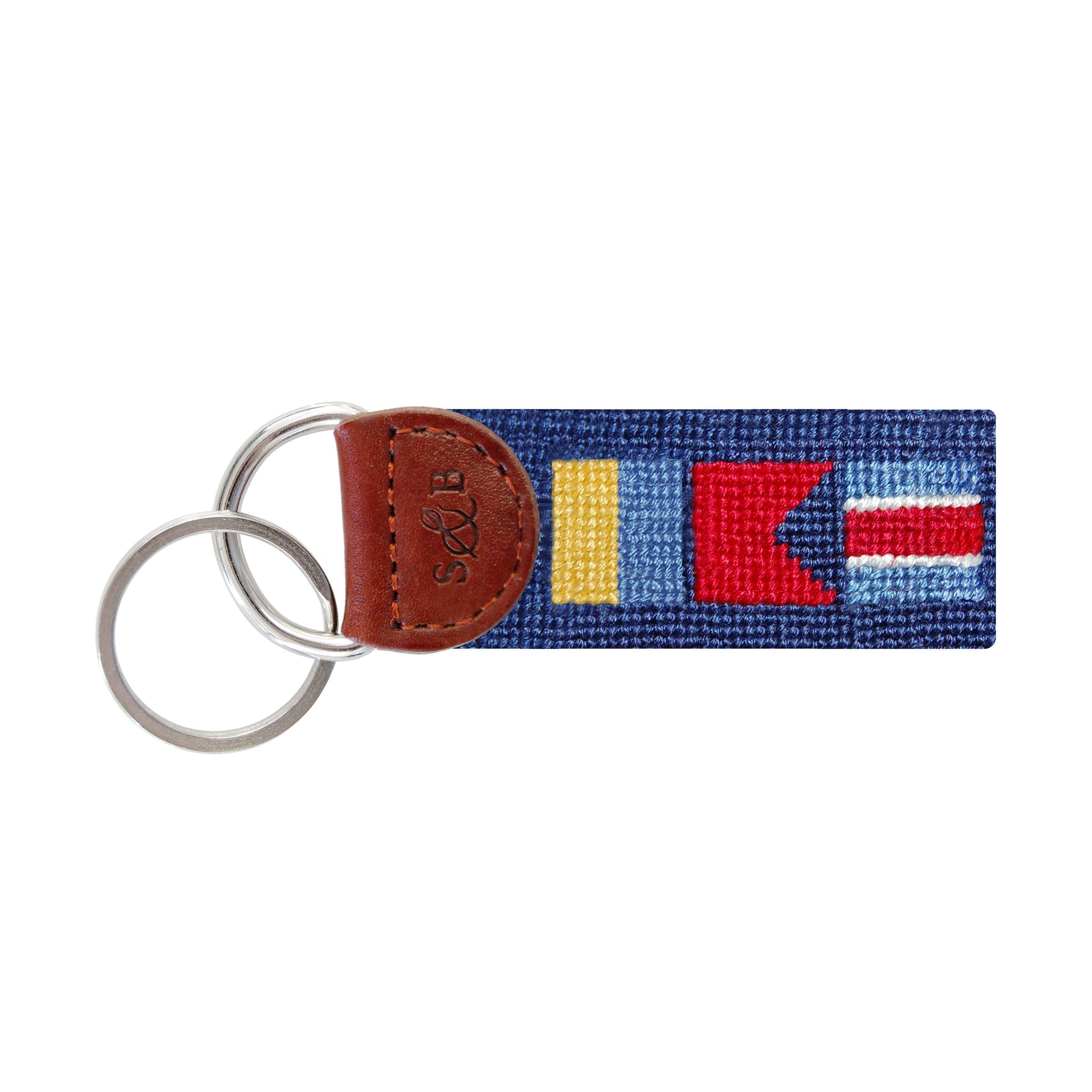 Navy needlepoint key fob displaying a nautical flag-style monogram, brown leather trim, and a metal key ring.