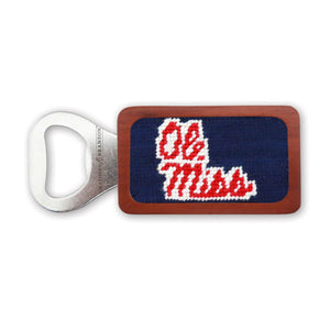 A stainless steel bottle opener with a wooden frame featuring a dark navy needlepoint design embroidered with the red and white “Ole Miss” script logo