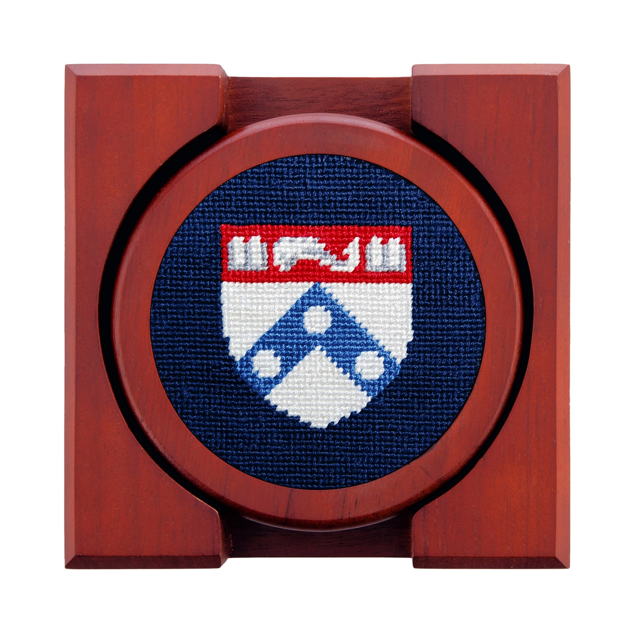 Set of four round wooden coasters with stitched needlepoint logos stacked neatly in a wooden holder.