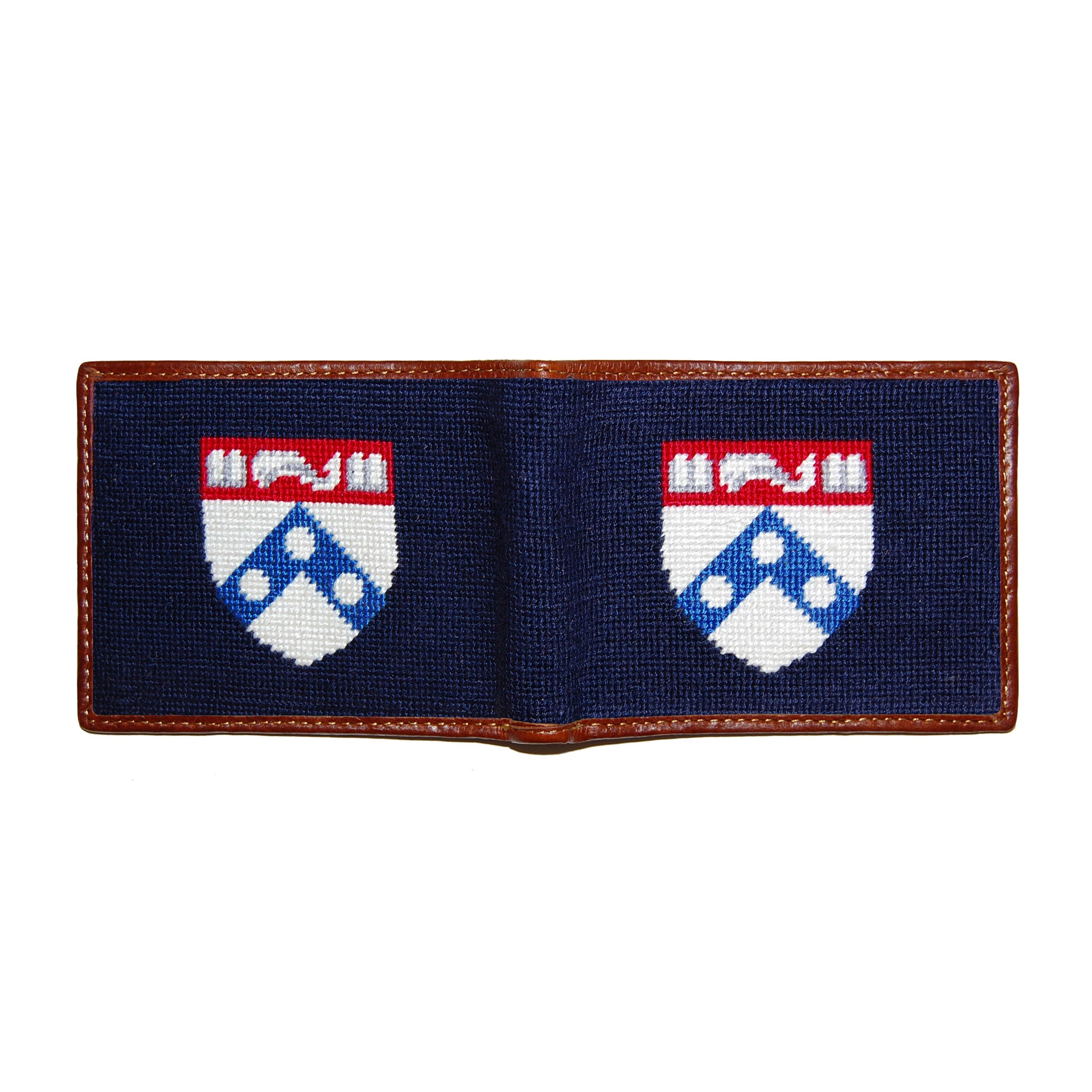 Pennsylvania navy needlepoint bi-fold wallet open to show both sides of the white “PENN” text needlepoint design with brown leather trim.