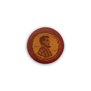 Golf ball marker designed to resemble a stitched penny on a tan background.