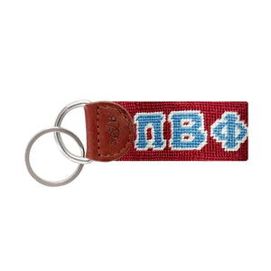 Maroon needlepoint key fob featuring the Greek letters ΠΒΦ in white, brown leather trim, and a metal key ring.