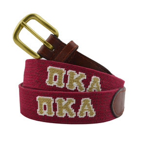 Pi Kappa Alpha Needlepoint Belt coiled, with brown leather trim and a brass buckle