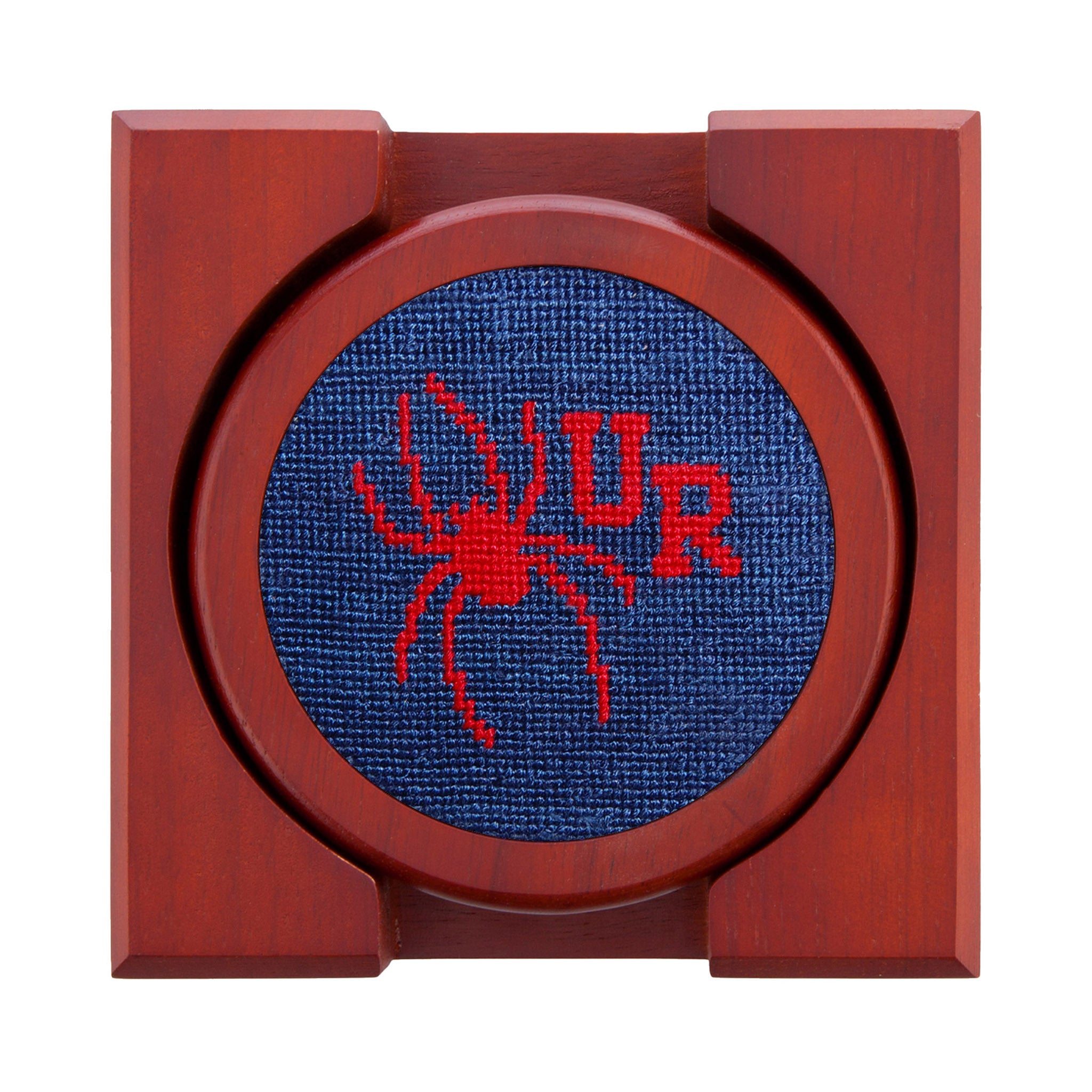 Set of four round wooden coasters with stitched needlepoint logos stacked neatly in a wooden holder.