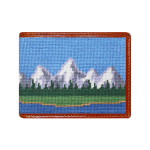 Multi-color mountain landscape needlepoint bi-fold wallet with brown leather trim, shown from primary angle.