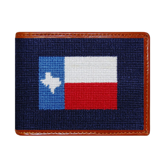 Dark navy needlepoint bi-fold wallet with Texas flag design, brown leather trim, shown from primary angle.