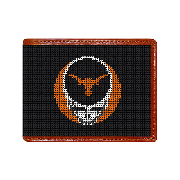 Black stitch-out stamped University of Texas Grateful Dead Steal Your Face needlepoint bi-fold wallet with brown leather trim, shown from primary angle.