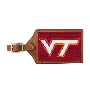 Maroon needlepoint luggage tag featuring the orange and white Virginia Tech “VT” logo, brown leather trim, and an ID window on the back.