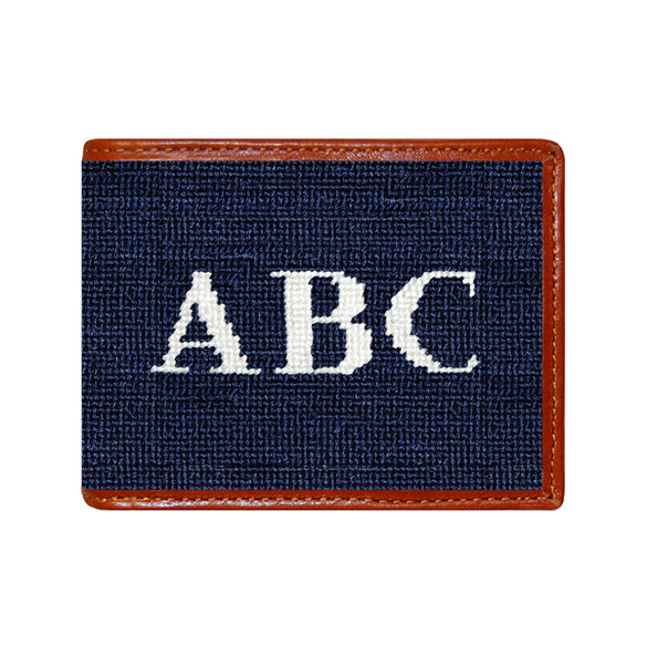 Black block monogram needlepoint bi-fold wallet with brown leather trim, shown from primary angle.