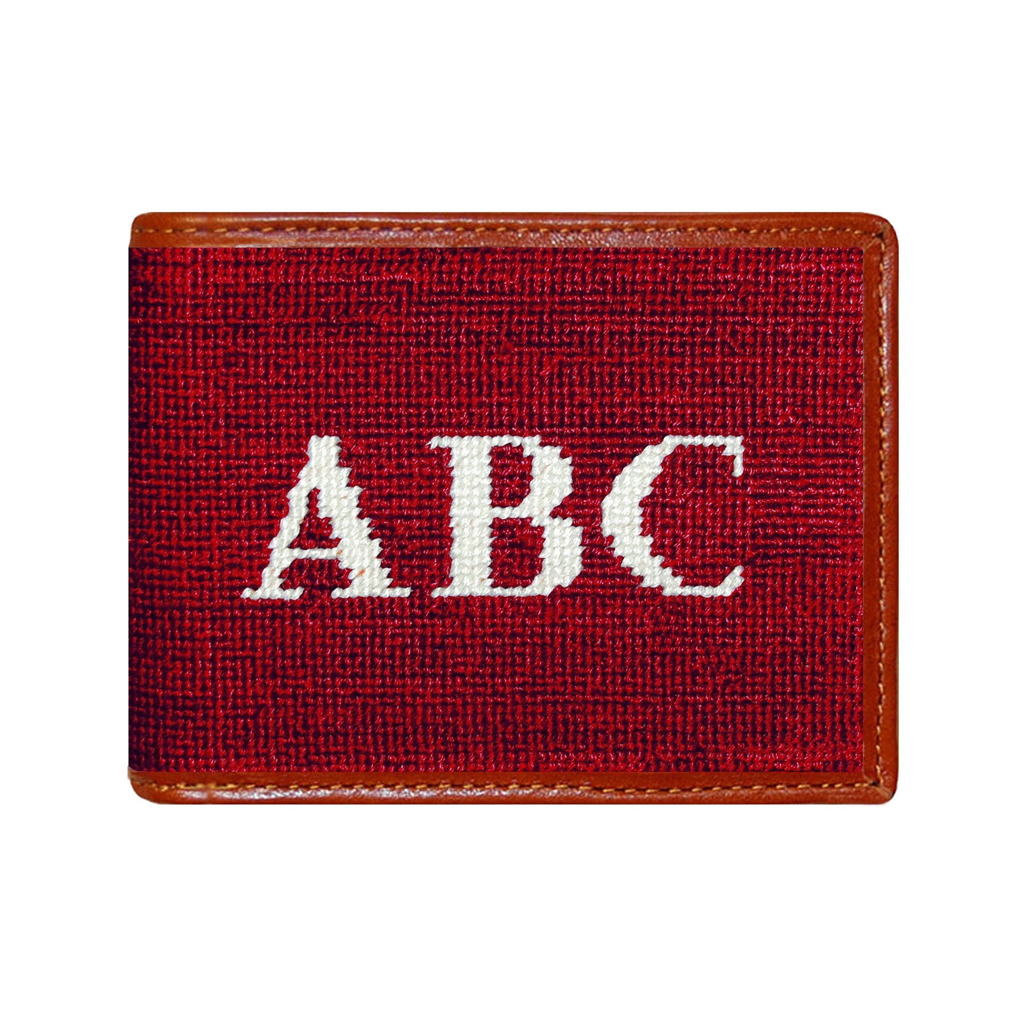 Nautical-themed needlepoint monogram bi-fold wallet with brown leather trim, shown from primary angle.
