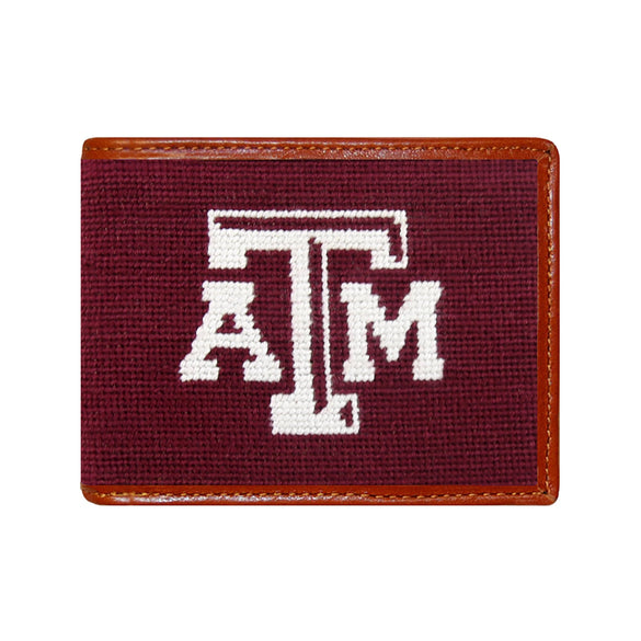 Brown leather bi-fold wallet with Texas A&M maroon needlepoint monogram, shown from primary angle.