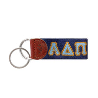 Azure blue needlepoint key fob with the Greek letters ΑΔΠ in white, brown leather trim, and a metal key ring.