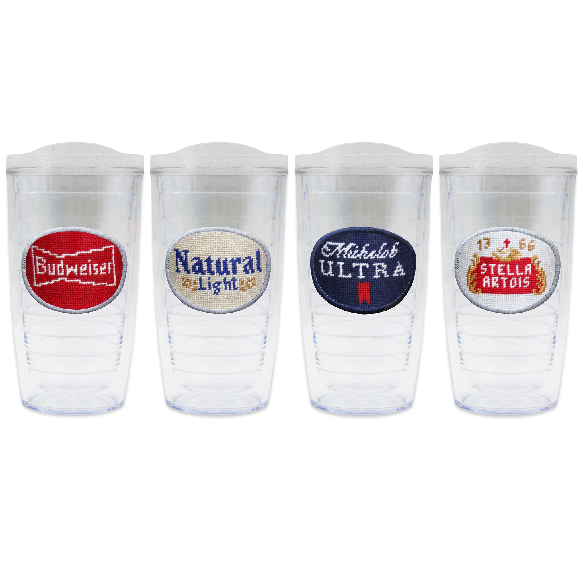 Set of 4 tumblers with lids on each in a line with a needlepoint logo in the center of each tumbler