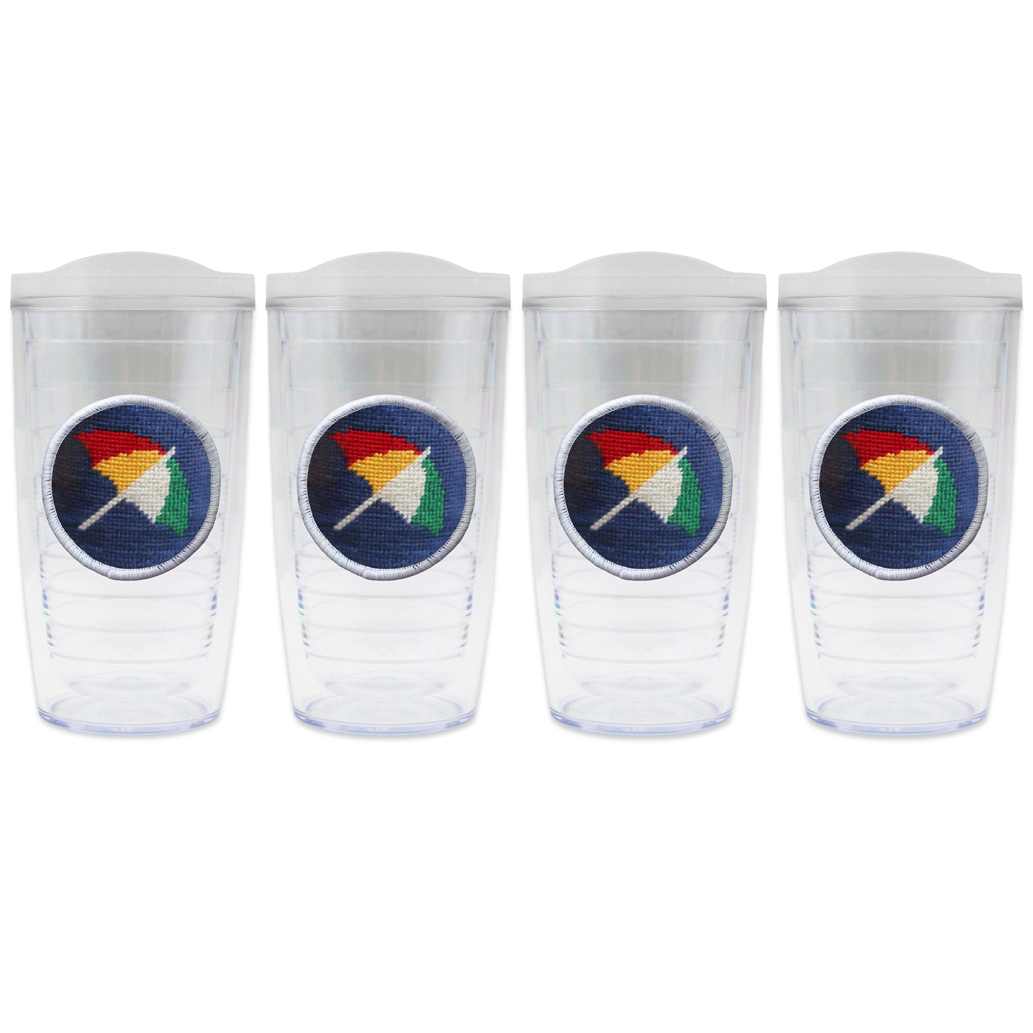 Set of 4 tumblers with lids on each in a line with a needlepoint logo in the center of each tumbler