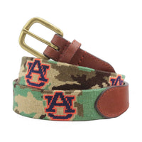Auburn Camo Needlepoint Belt Final Sale coiled, with brown leather trim and a brass buckle