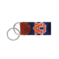Navy needlepoint key fob with the orange Auburn University “AU” logo, brown leather trim, and a metal key ring.