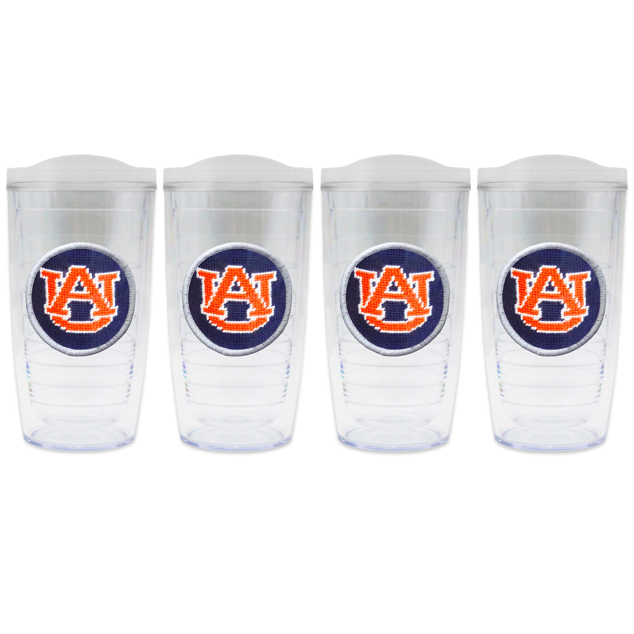 Set of 4 tumblers with lids on each in a line with a needlepoint logo in the center of each tumbler