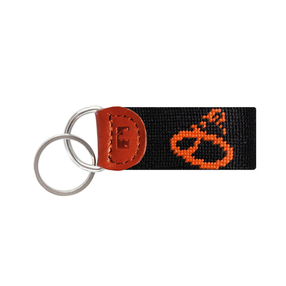 Orange needlepoint key fob with the cartoon Baltimore Orioles bird logo, brown leather trim, and a metal key ring.