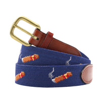Blue needlepoint cigar belt with brown leather strap and brass buckle on a white background