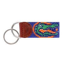 Royal blue needlepoint key fob featuring the orange and green Florida Gators alligator head logo, brown leather trim, and a metal key ring.