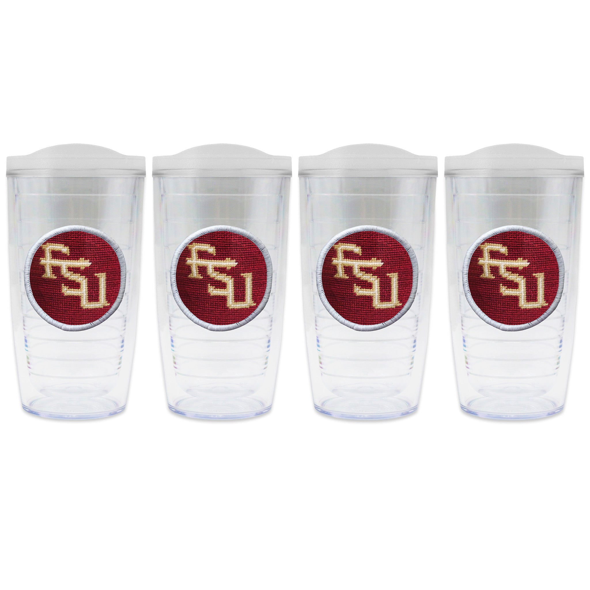 Set of 4 tumblers with lids on each in a line with a needlepoint logo in the center of each tumbler
