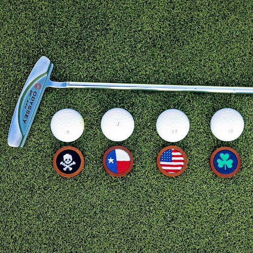 array of golf ball markers lined up on a putting green